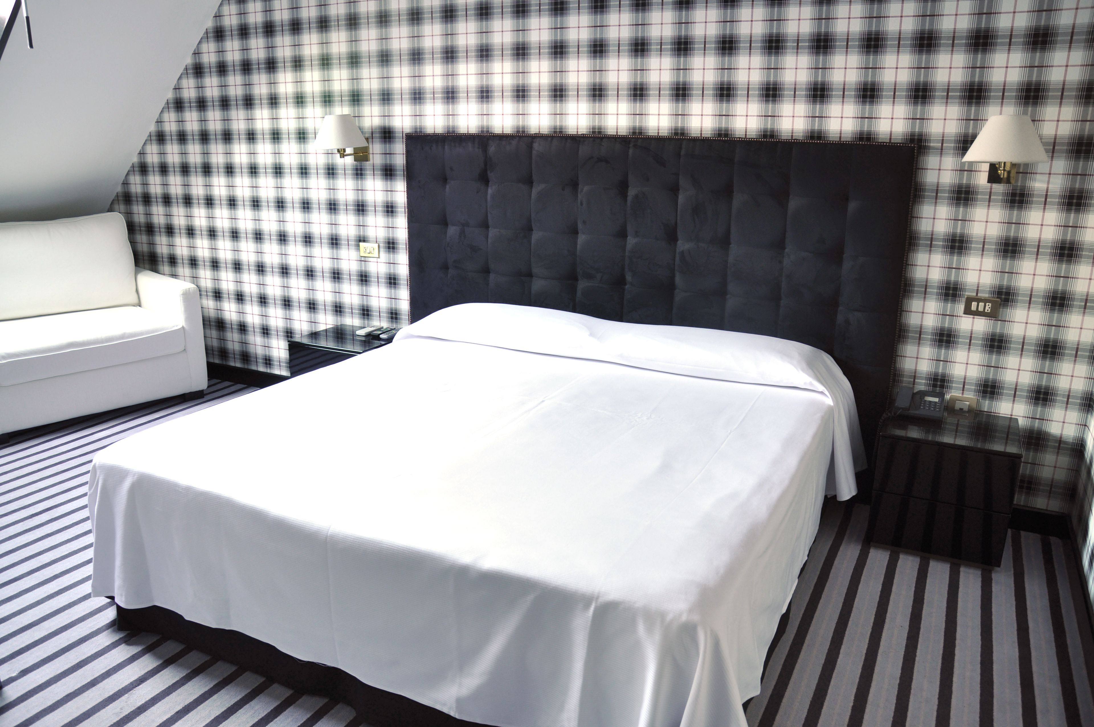 Una habitación de hotel con una cama grande, un sofá blanco y un estampado de cuadros en la pared.