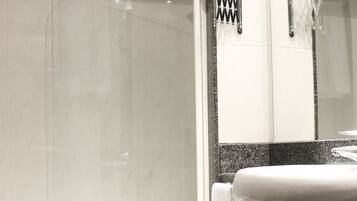 A modern bathroom with a glass-enclosed shower, a white toilet, and a sink with a mirror.