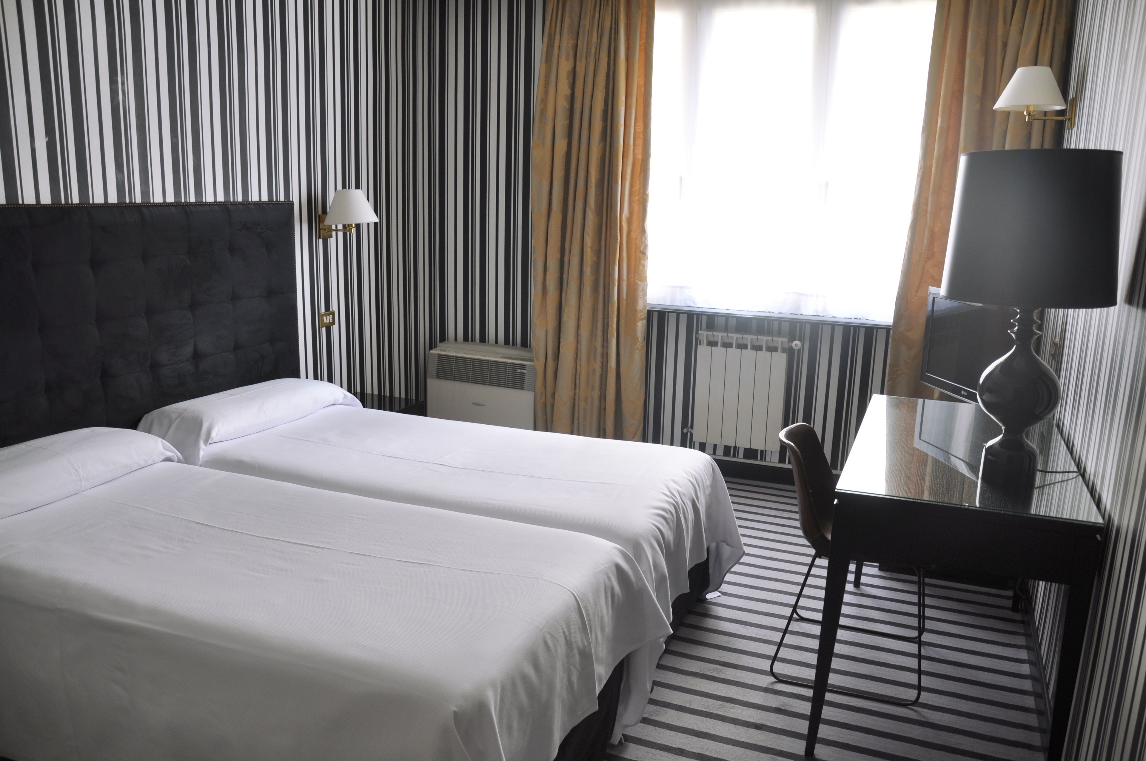 Een hotelkamer met twee bedden, een bureau en een stoel.