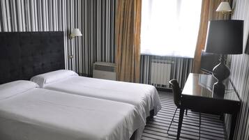 Een hotelkamer met twee bedden, een bureau en een stoel.