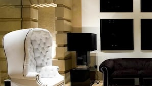 Ein modernes Wohnzimmer mit einem weißen Sessel, einer schwarzen Stehlampe und einem dunklen Sofa.