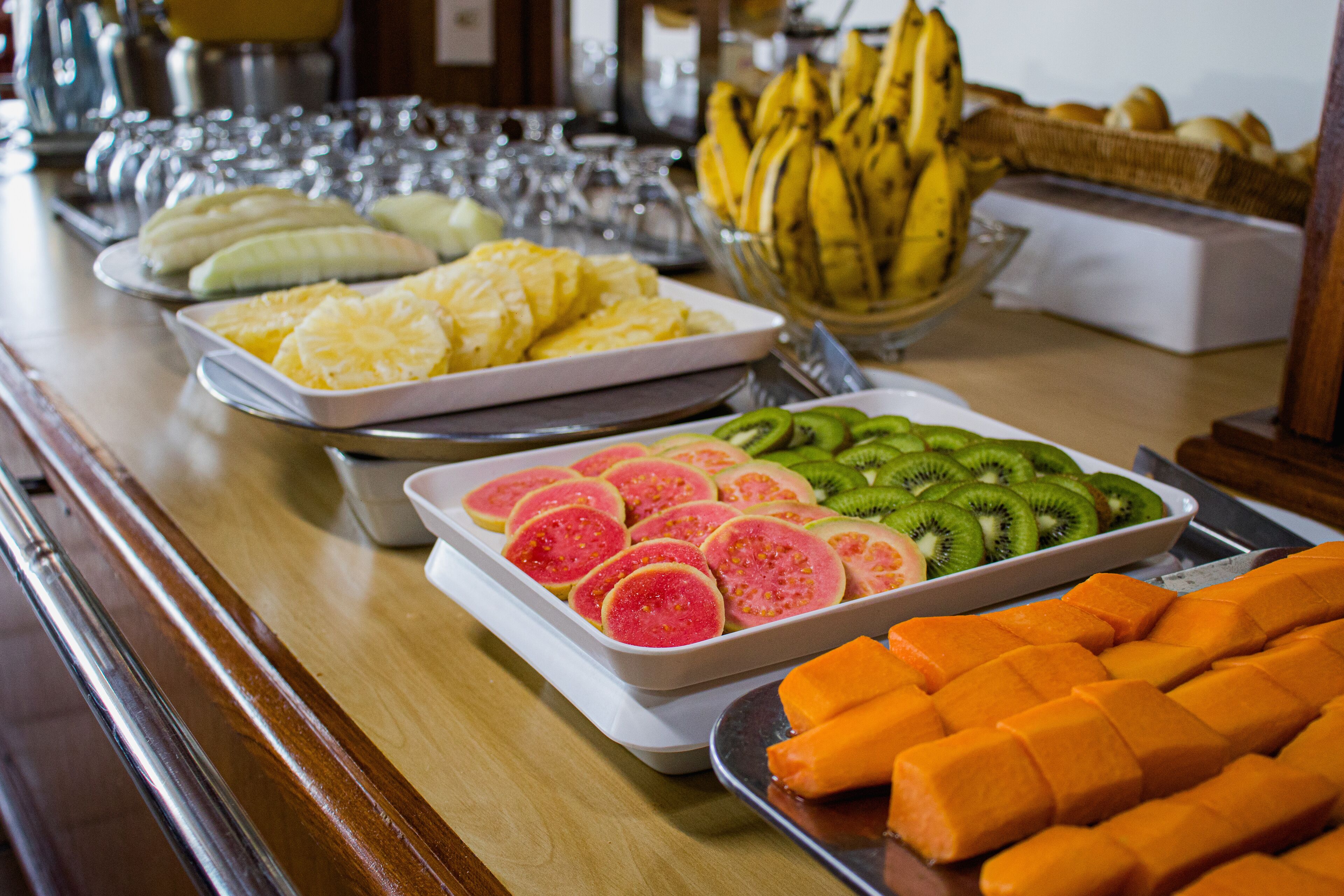 A buffet table with various fruits and a bowl of bananas.
