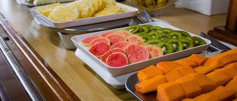 A buffet table with various fruits and a bowl of bananas.