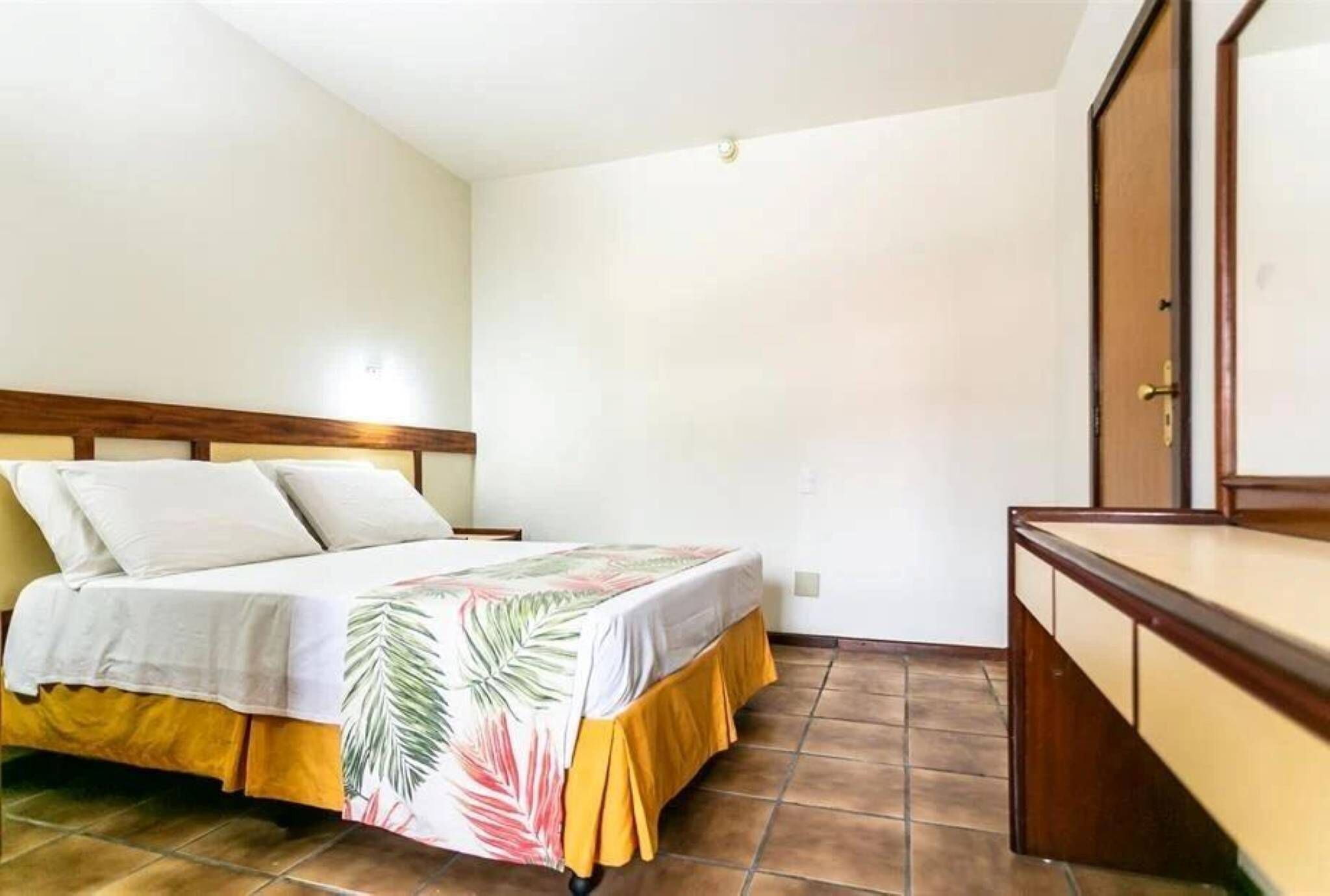 Quarto com cama, cabeceira de madeira, mesa de cabeceira e guarda-roupa.