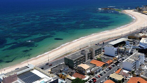 Un paisaje urbano costero con playa, edificios y una carretera.