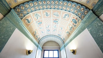 A ceiling with a circular pattern and a window at the end of a hallway.