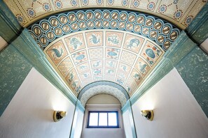 A ceiling with a circular pattern and a window at the end of a hallway. - Hotel Alt-Connewitz (Leipzig)
