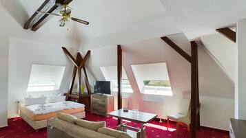 Ein Zimmer mit einem Bett, einem Schreibtisch, einem Sessel, einem Fernseher und einem Deckenventilator.