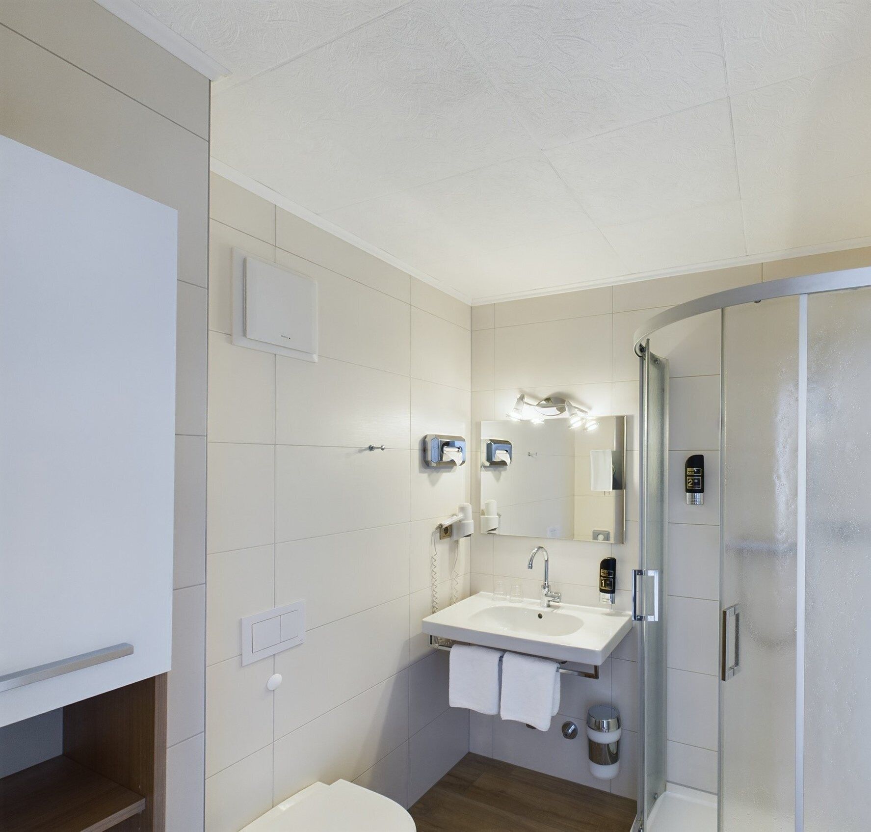 Een moderne badkamer met een wit wastafelmeubel, spiegel en een douchecabine van glas.