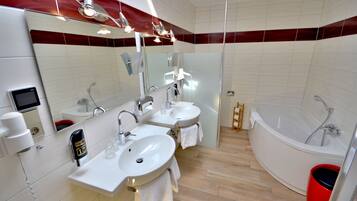 A modern bathroom with two sinks, a large mirror, a shower, and a red bucket.