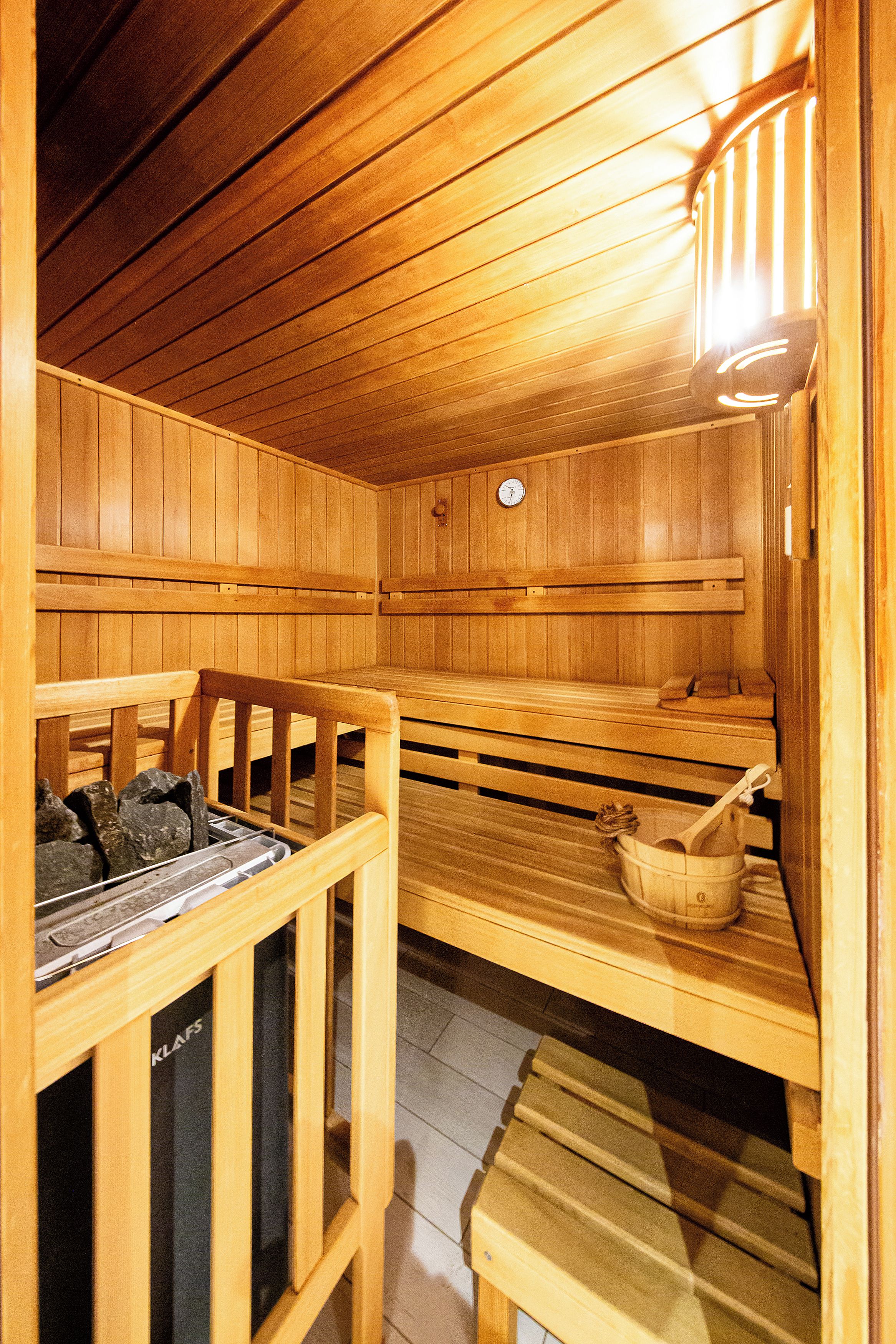 Un sauna con bancos de madera y un asiento con un cubo.