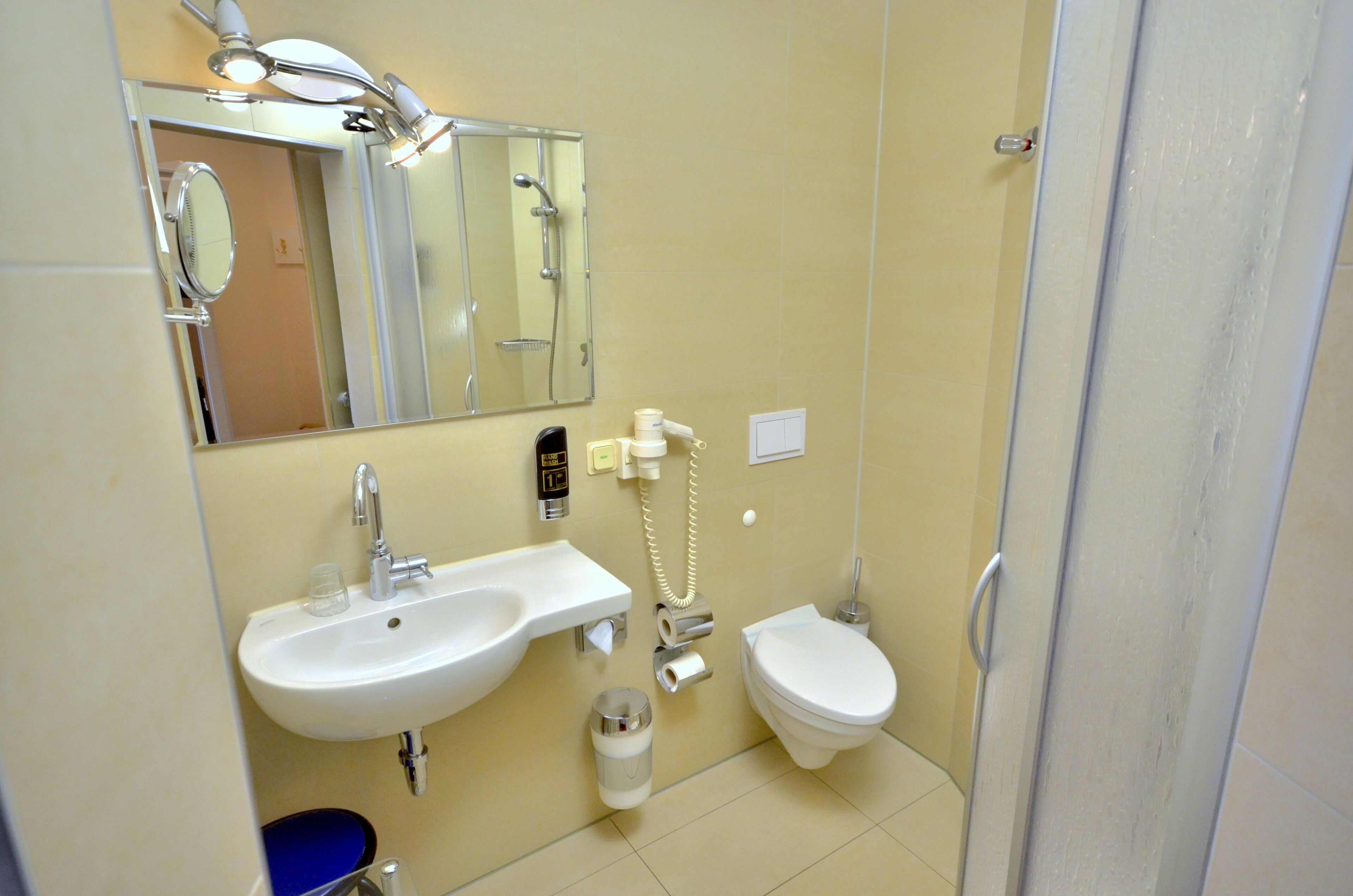 A bathroom with a sink, mirror, toilet, and shower.