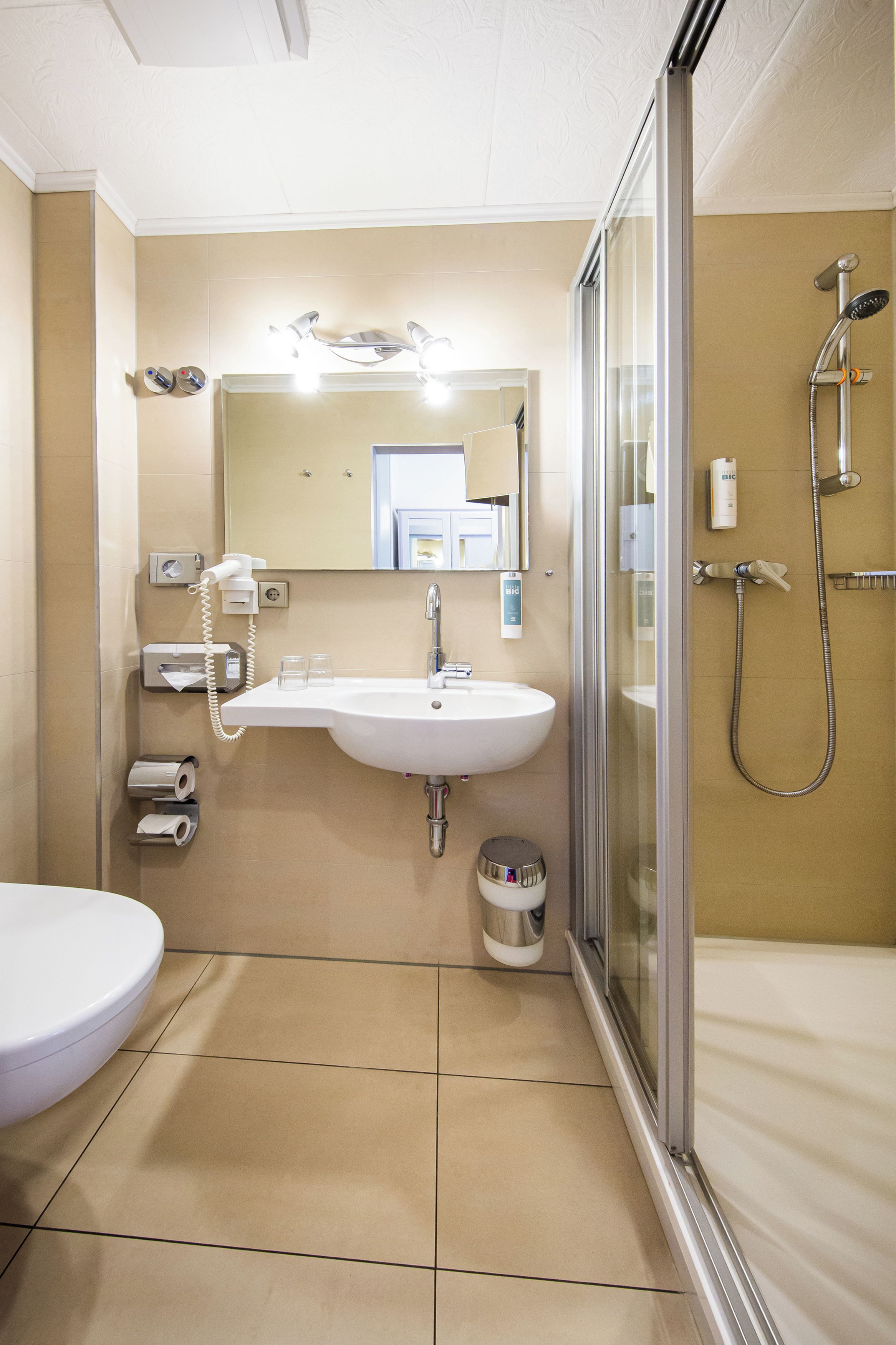 A bathroom with a white sink, mirror, and shower.
