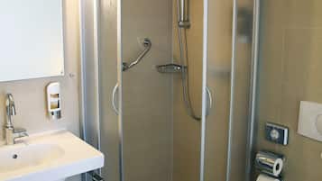 Et moderne badeværelse med bruseniche, håndvask med spejl og toilet.
