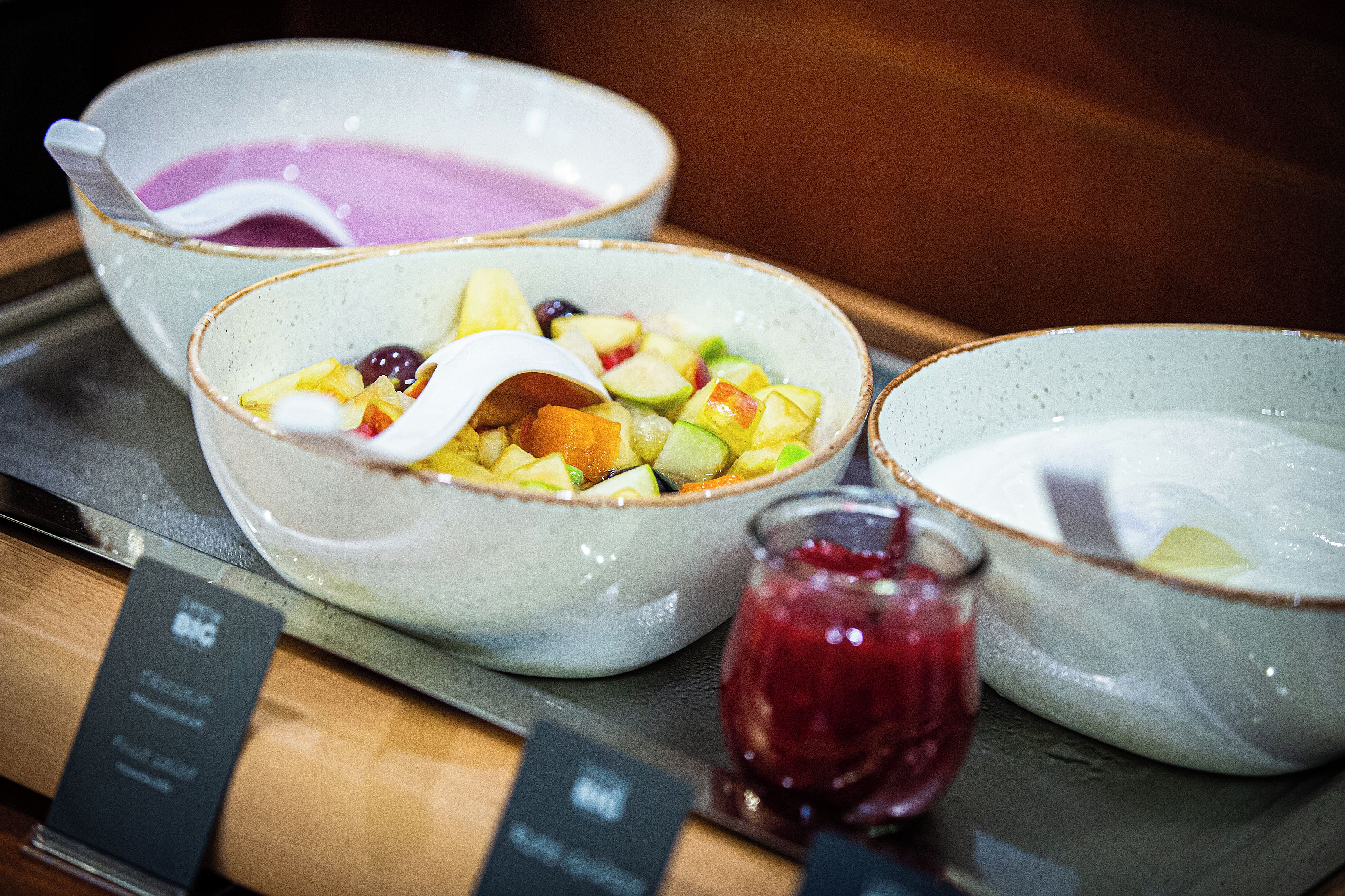 Three bowls of fruit salad with a small jar of jam.