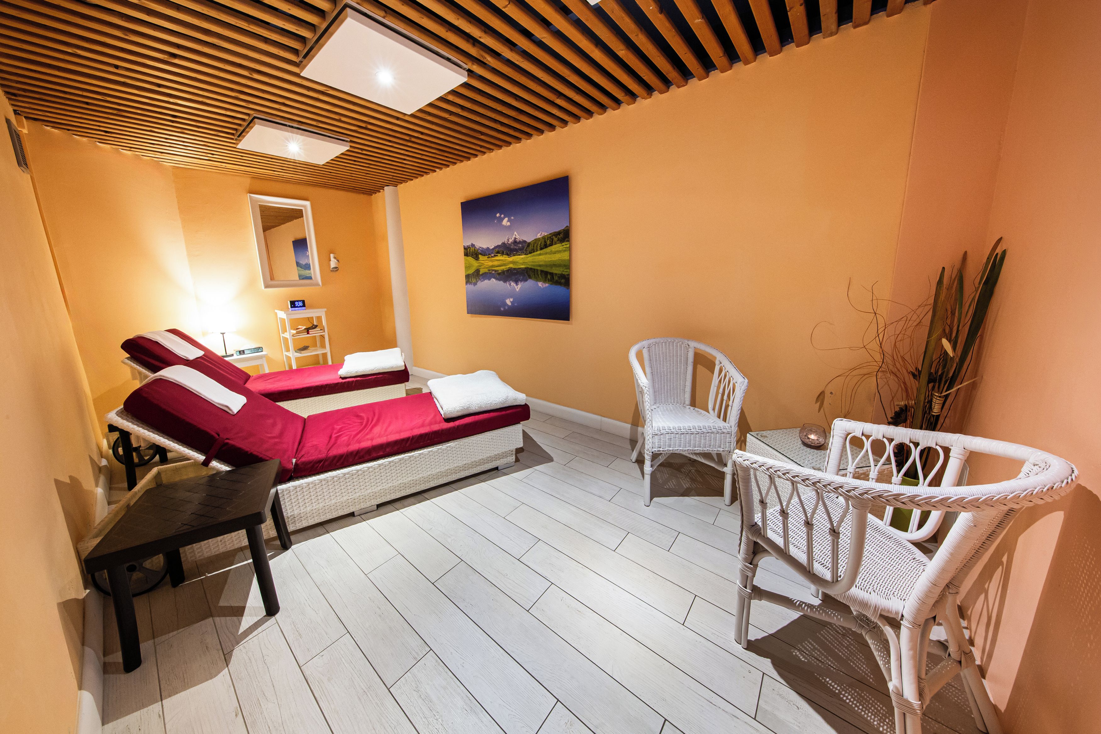 Una habitación con dos camas, una silla, una mesa y un cuadro en la pared.