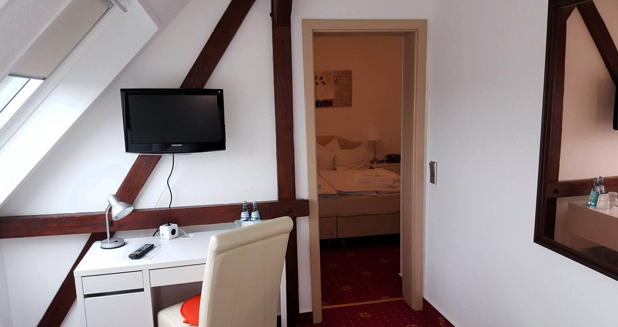 Ein Hotelzimmer mit Schreibtisch, Stuhl, Fernseher und Bett.