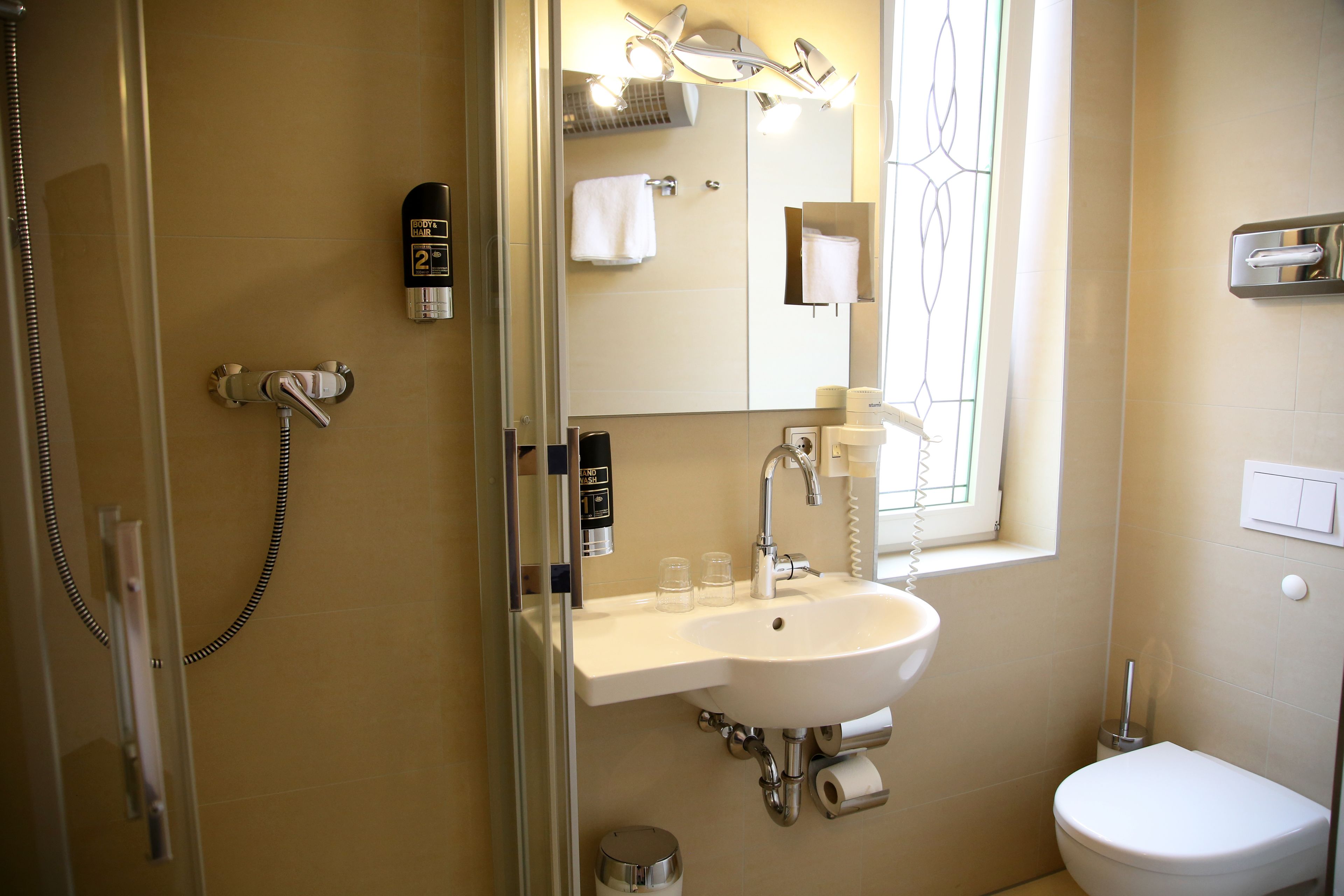 Un baño con ducha, lavamanos, inodoro y espejo.
