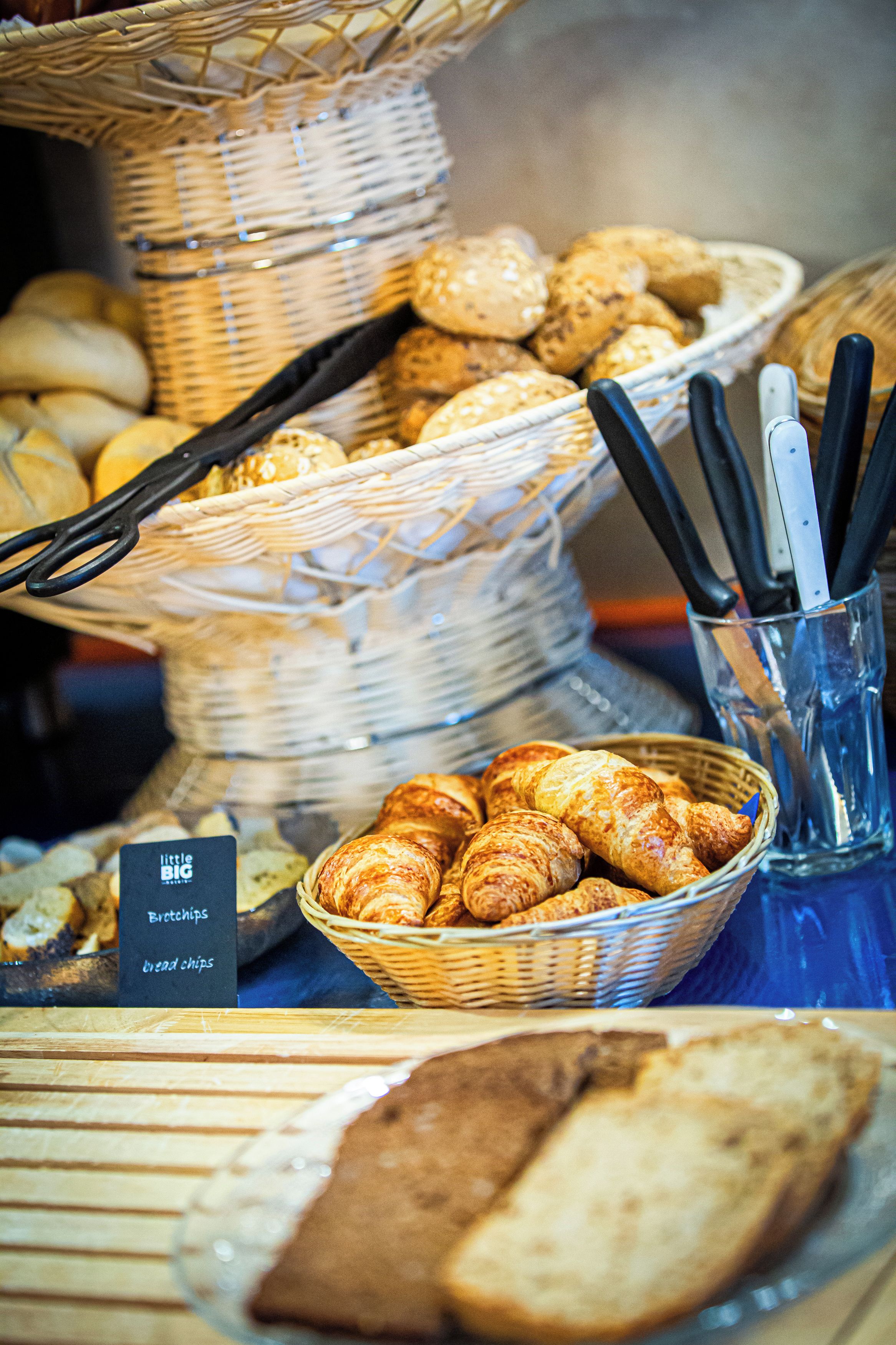 Een buffet met manden vol brood, croissants en een bordje met 'broodchips' en 'broodchips'.