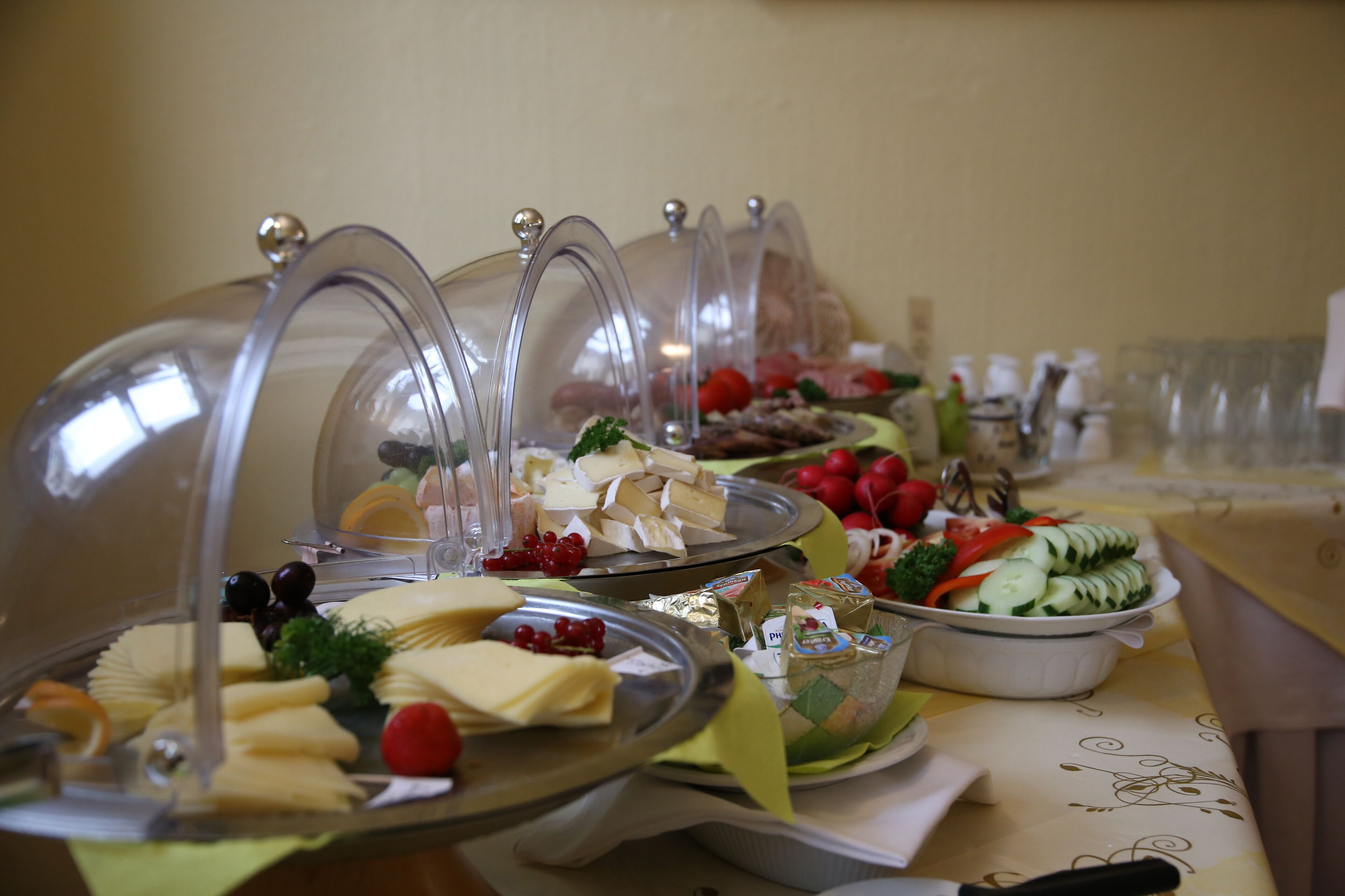 A buffet table with various food items and beverages, covered with clear dome lids.