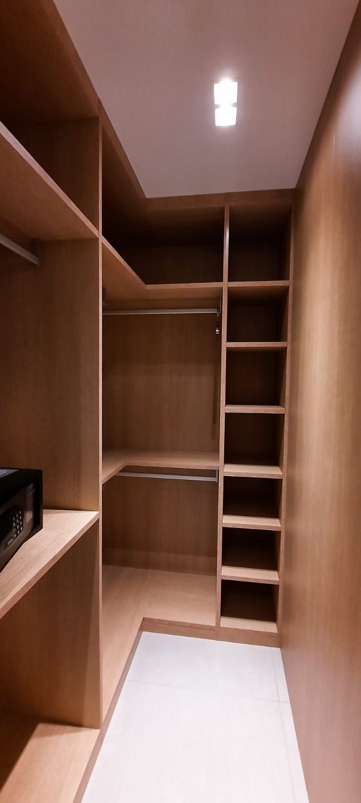 Um closet espaçoso com várias prateleiras e barra para pendurar roupas, com uma luminária no teto.