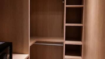 Um closet espaçoso com várias prateleiras e barra para pendurar roupas, com uma luminária no teto.