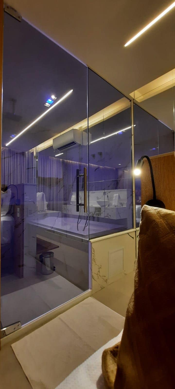 Een moderne badkamer met een glazen douchecabine, een wastafel en een toilet.