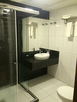 Un baño moderno con cabina de ducha de vidrio, un lavabo blanco y un inodoro.