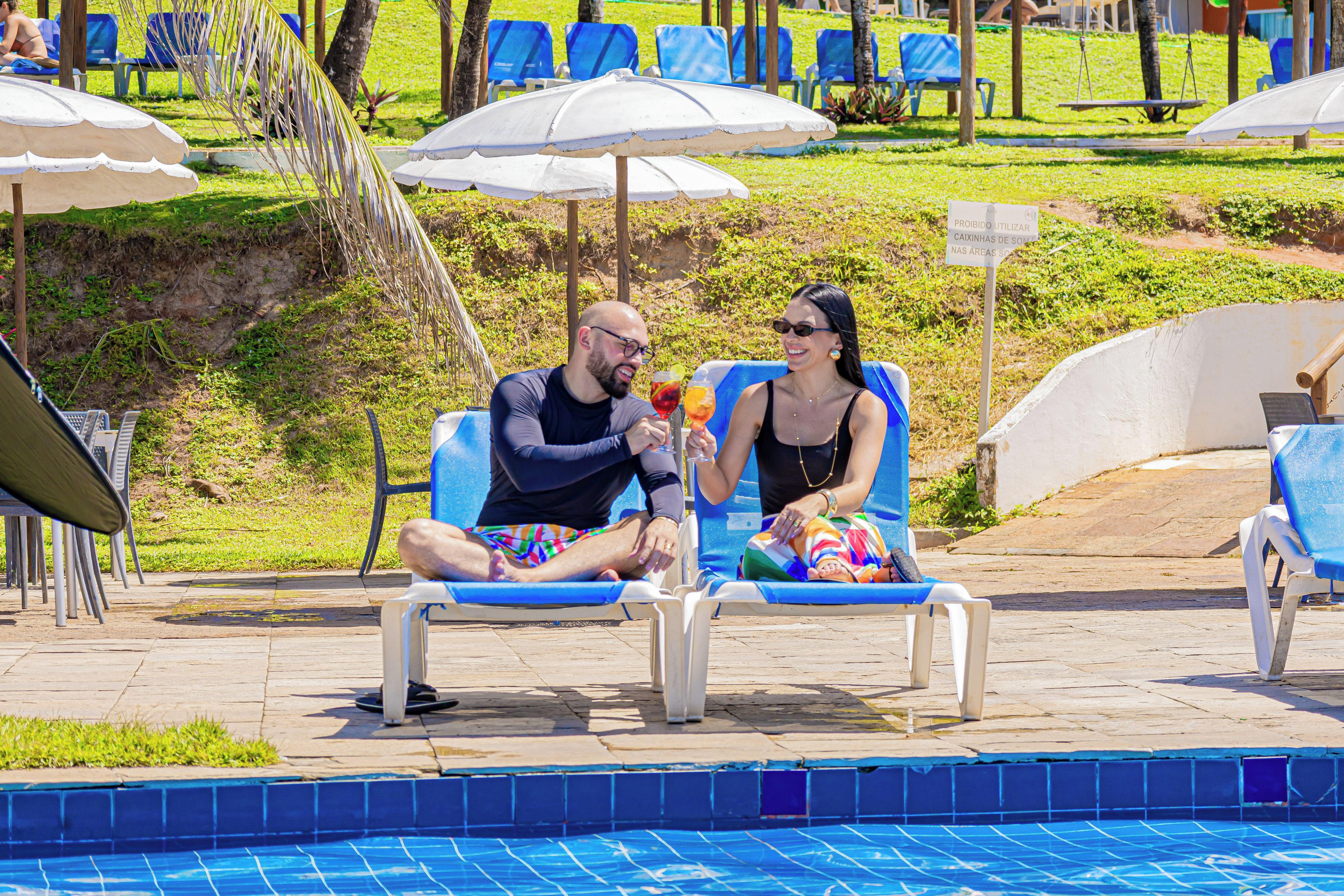 Un área junto a la piscina con sillones de descanso y sombrillas.