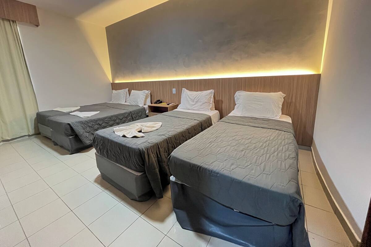 A hotel room with two single beds, a nightstand, and a large wall-mounted light.