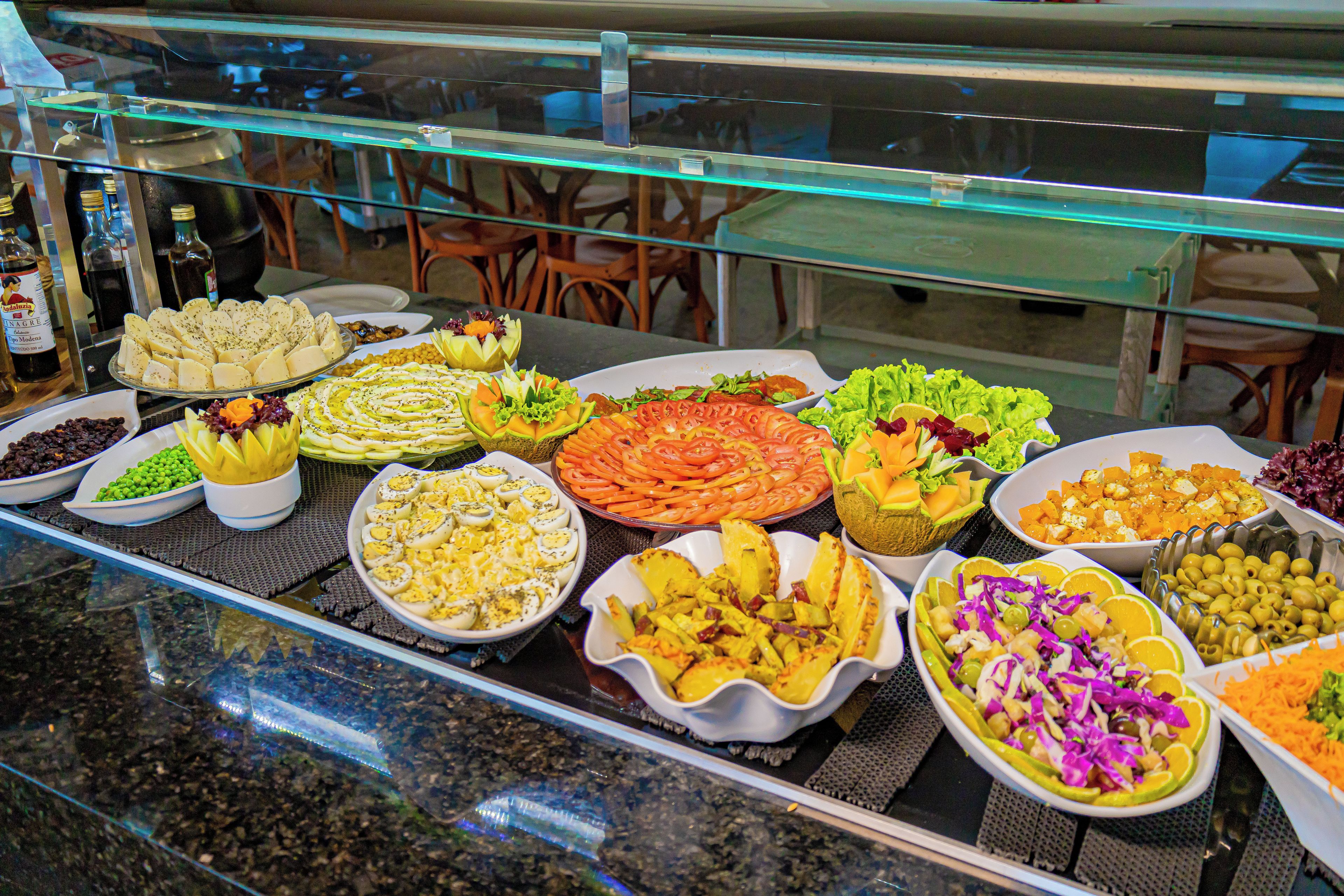 Un bufé con diversos platos, incluyendo ensaladas, quesos y frutas.