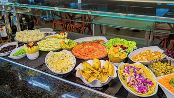 Un bufé con diversos platos, incluyendo ensaladas, quesos y frutas.