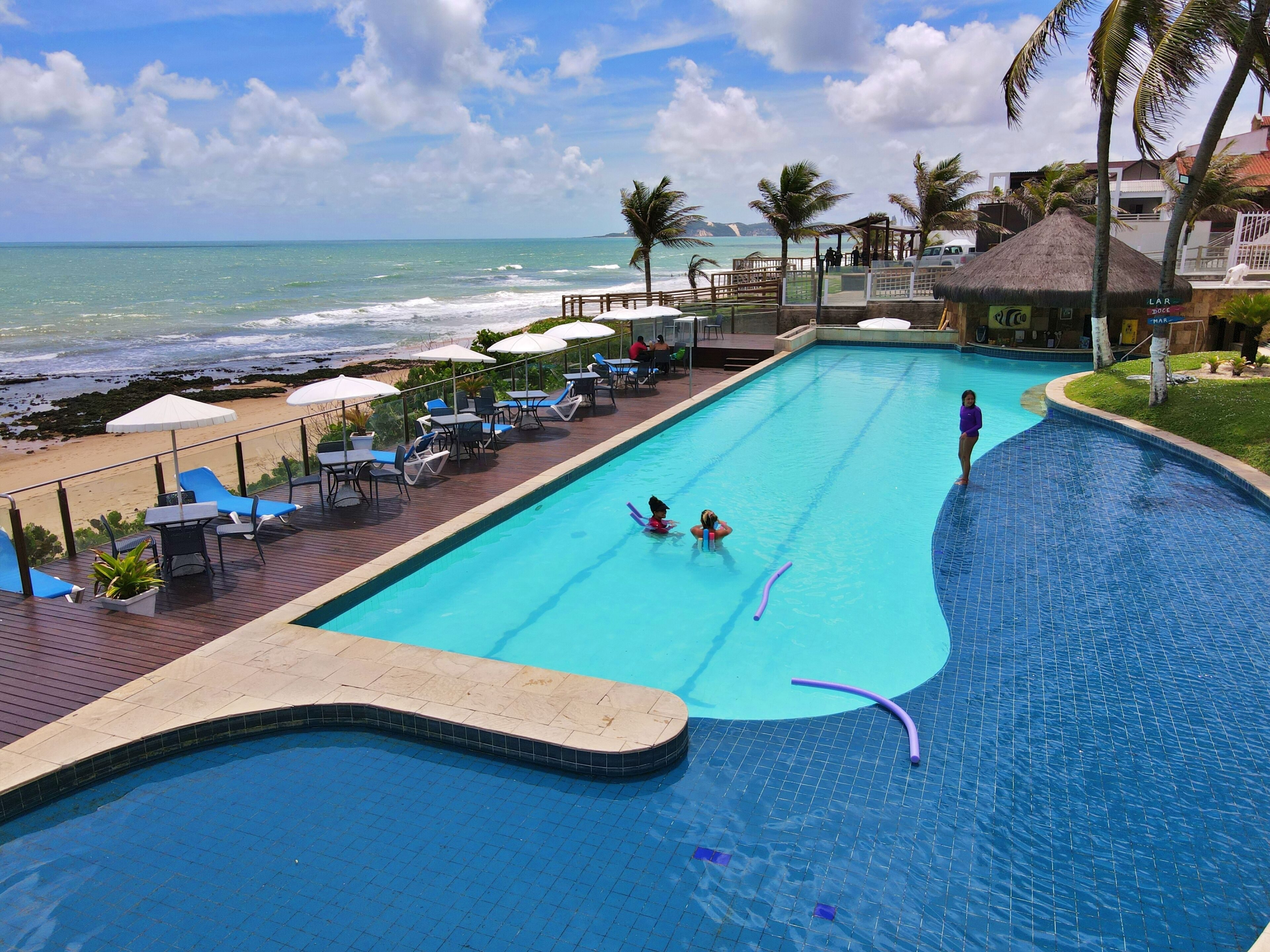 Ein Pool mit Blick auf den Ozean, Liegestühle und Sonnenschirme.