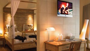Un dormitorio con cama de madera, mesita de noche y televisor montado en la pared.
