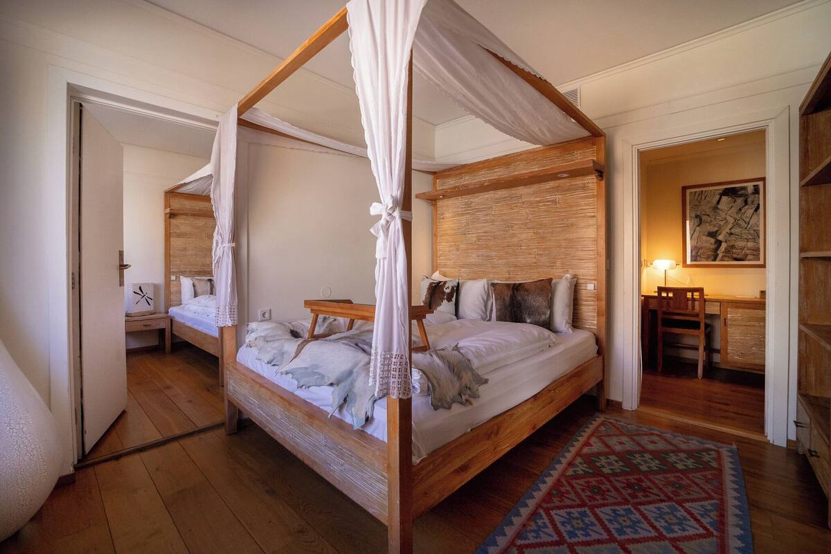 A four-poster canopy bed with a wooden headboard, a bedside table, and a nightstand.