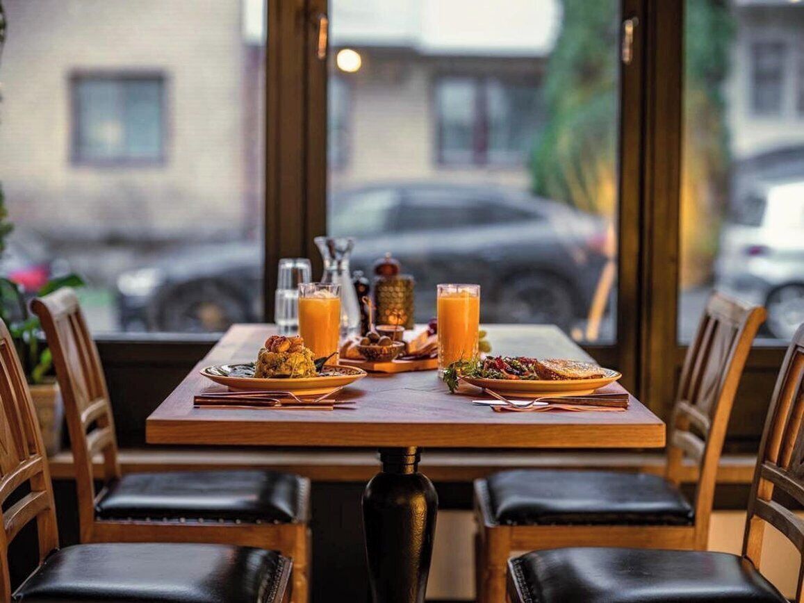 Una mesa de restaurante con comida, bebidas y vistas a la calle a través de amplios ventanales.