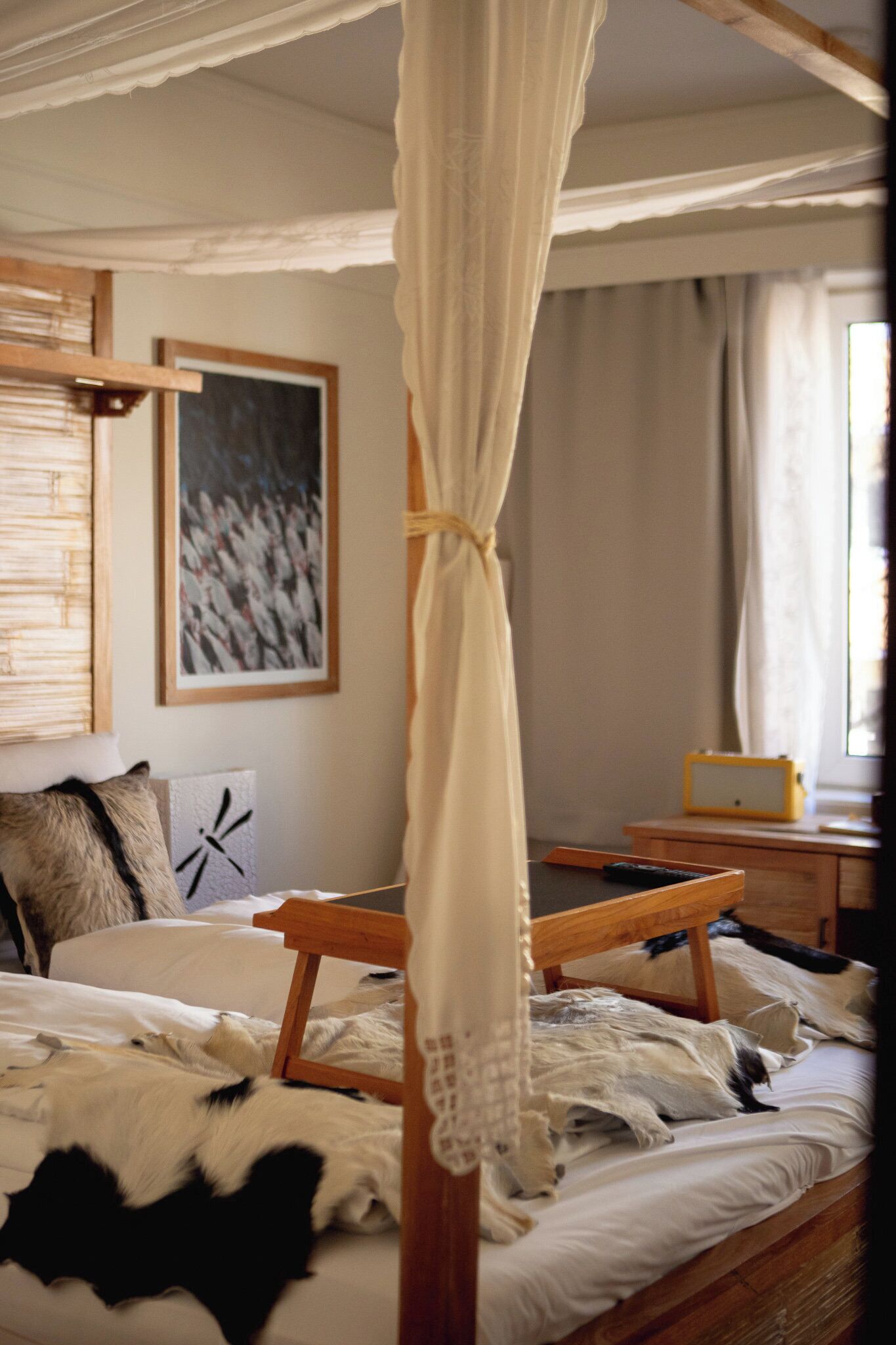 Un dormitorio con cama a dosel, cabecera de madera y un cuadro abstracto enmarcado en la pared.