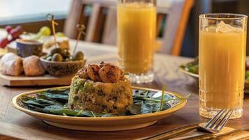 Esmorzar amb un plat de menjar, dues flaites de suc d'aranja i un bol d'olives.