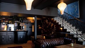 Un espace bar comprenant un comptoir, des tabourets de bar et un escalier doté d’une rampe en métal.