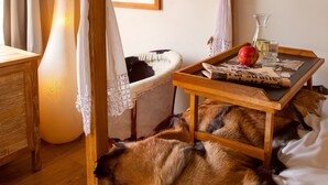 Une pièce chaleureuse avec un lit en bois, une table de chevet avec une lampe, un tableau encadré au mur et une fenêtre avec des rideaux.