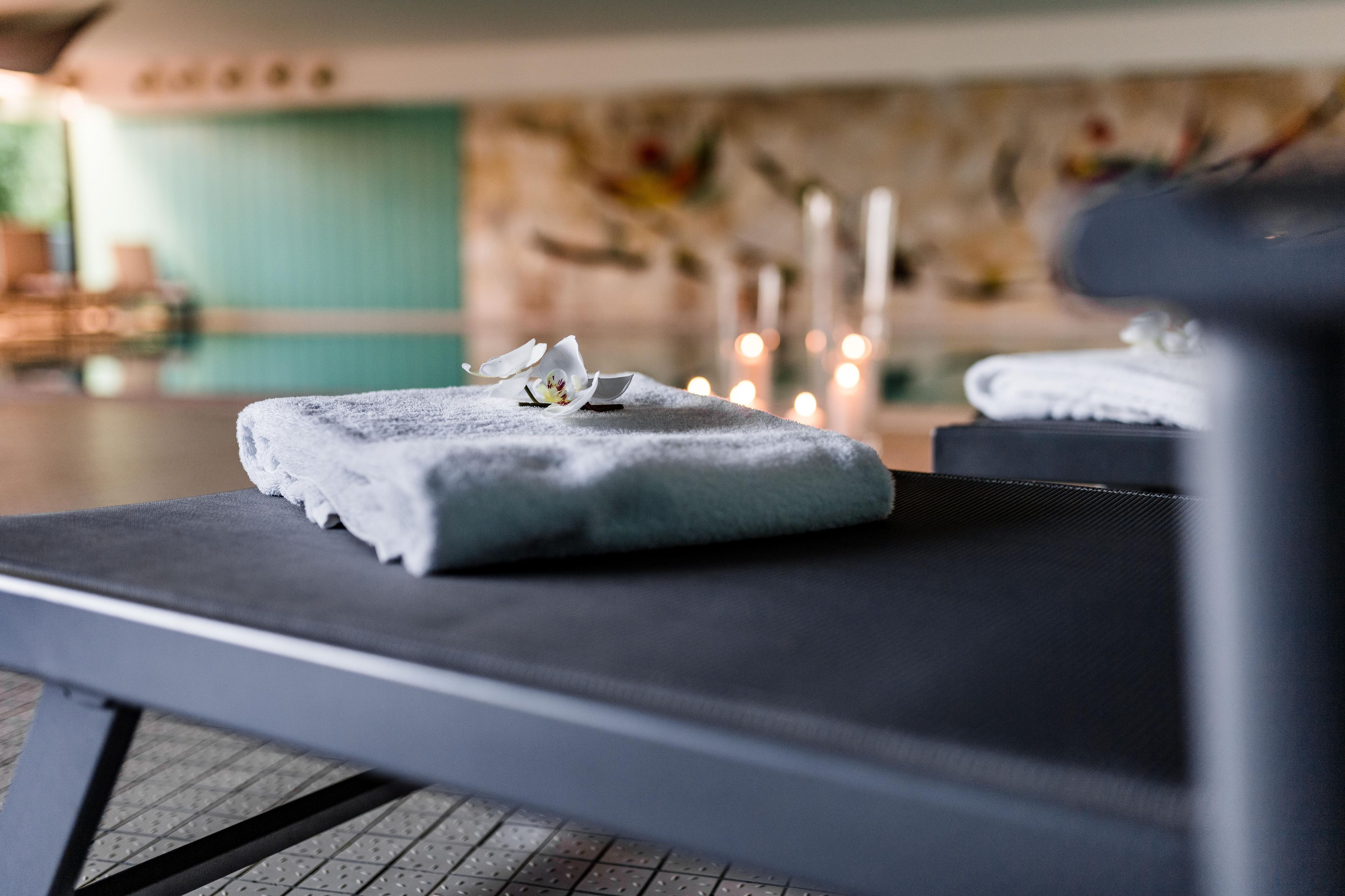 Ein Massagetisch mit Handtuch und Orchidee.