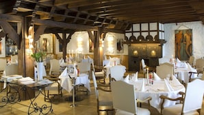 Un restaurante con mesas redondas, sillas blancas y un techo de madera rústica.