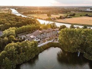 Een hotel met een binnentuin, omringd door bomen en een rivier.