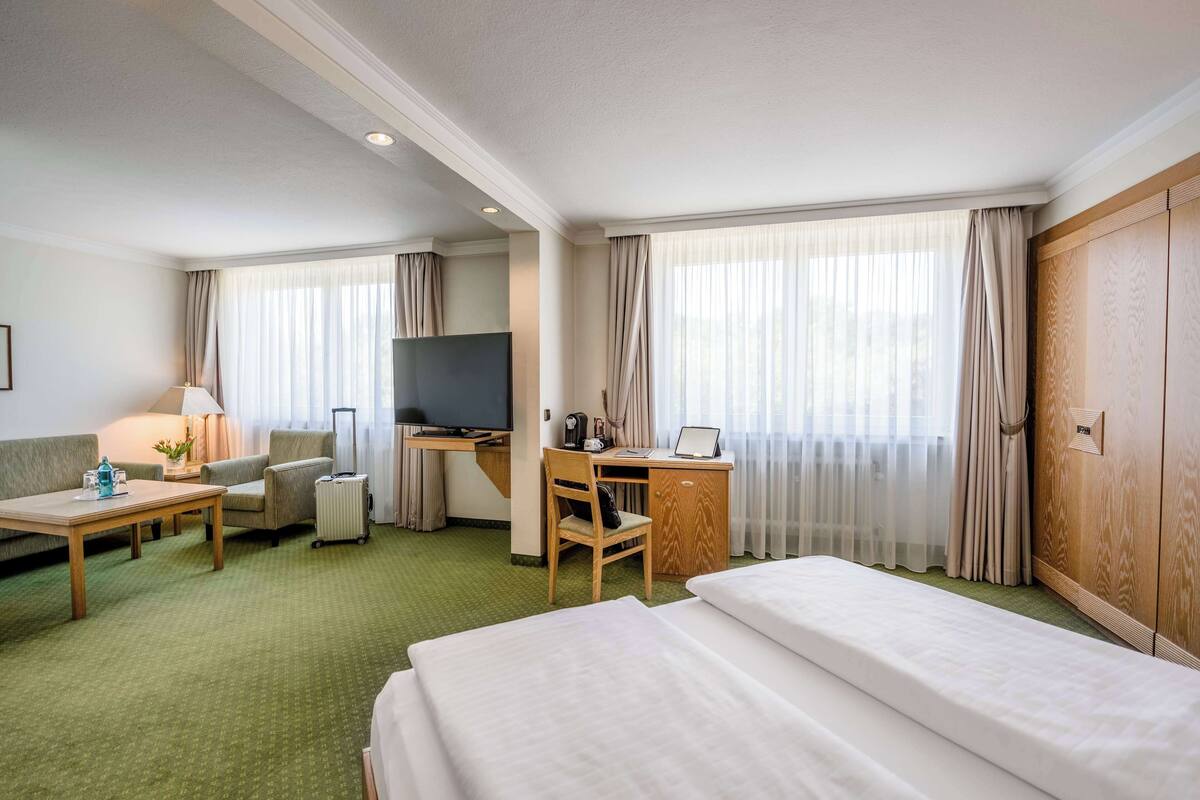 Een hotelkamer met twee bedden, een bureau met stoel, een televisie en een raam met gordijnen.