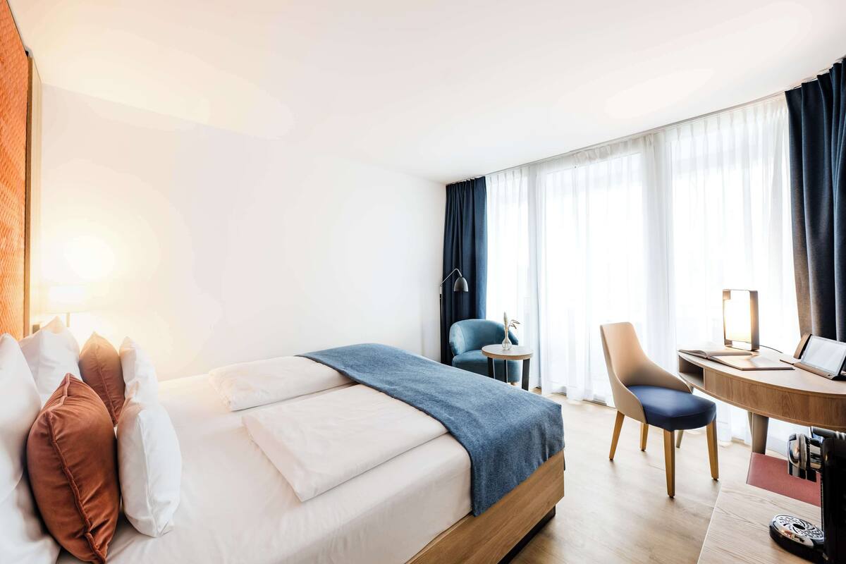 Een hotelkamer met een bed, bureau, stoel en lamp.