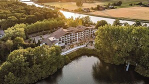 Luchtbeeld van een hotel met een binnentuin, omringd door bomen en een rivier.