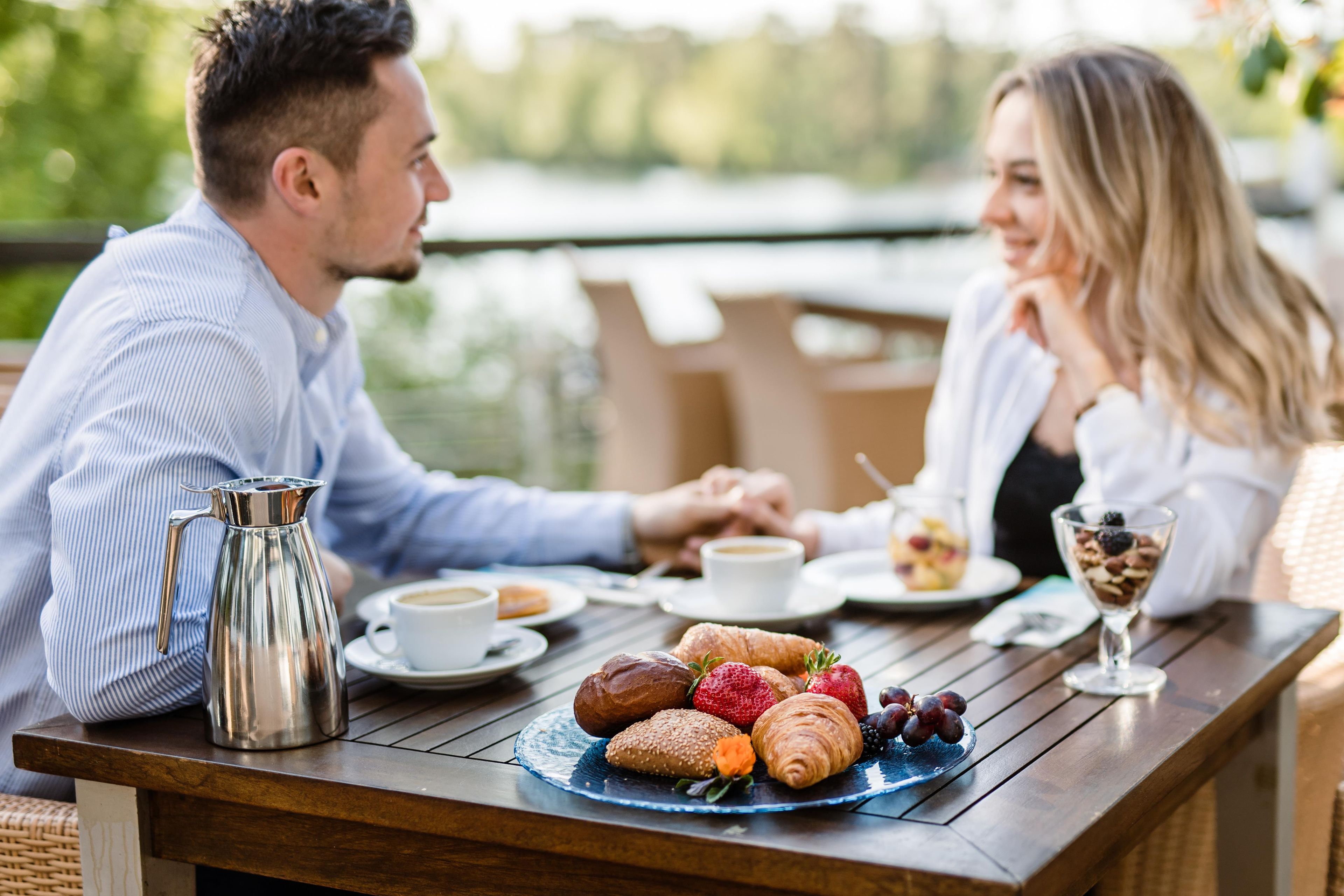 Ein Esstisch mit einer Kaffeekanne, Tellern und verschiedenen Backwaren und Früchten.