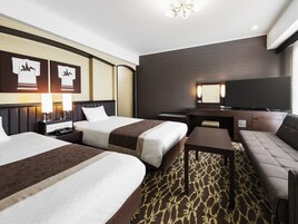 A hotel room with two beds, a TV, a desk, and a sofa.