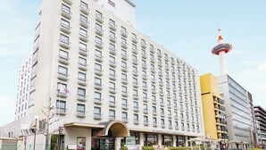 Un hotel de varios pisos con una entrada destacada, una torre con parte superior roja y blanca, y cielo despejado.