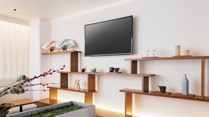 Una sala de estar moderna con un televisor de pantalla plana montado en la pared, estantes de madera con objetos decorativos y un jardín vertical con follaje verde.